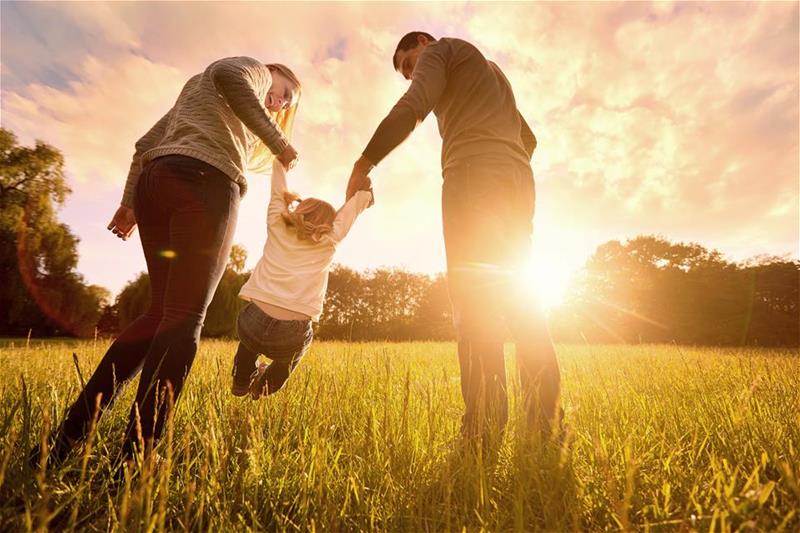 A couple swinging their young child between them