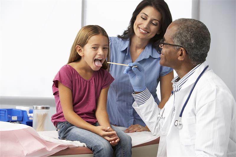 A physician looks inside young girl's throat