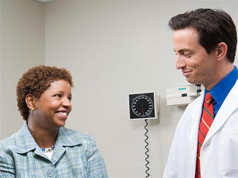 A woman having conversing with a doctor in an exam room