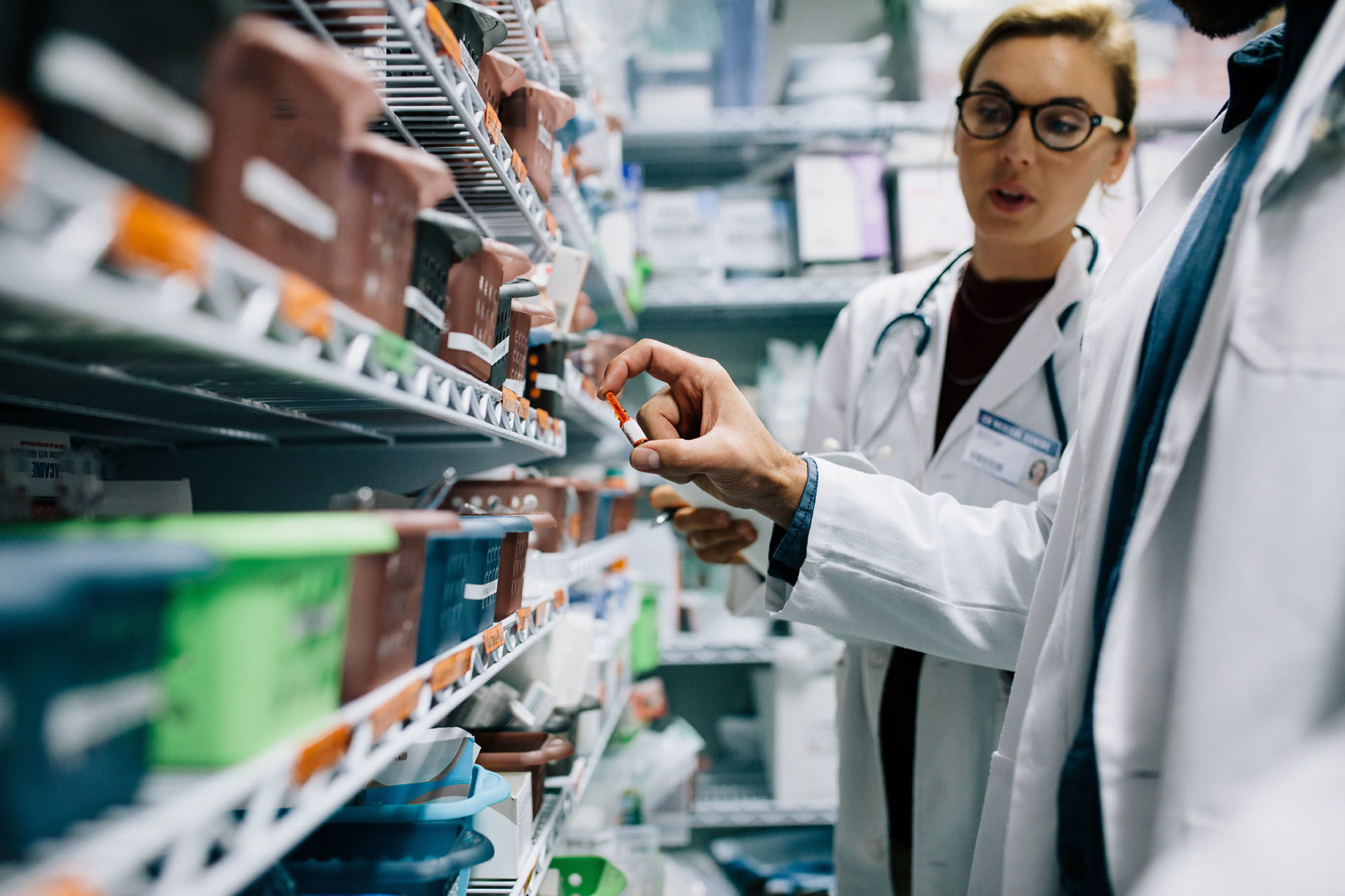 Two healthcare professionals reviewing medication bins