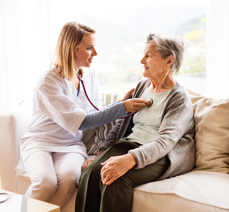 A health care provider listening to elderly woman's heart with a stethoscope