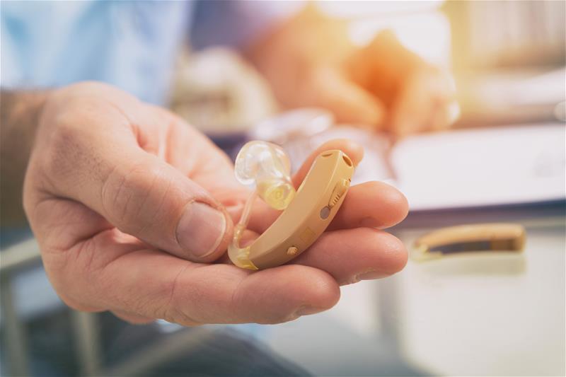 An individual holding a hearing aid