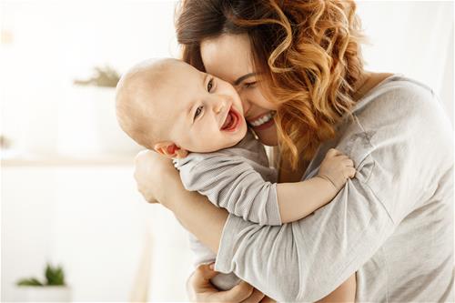 Mom snuggling a baby laughing together