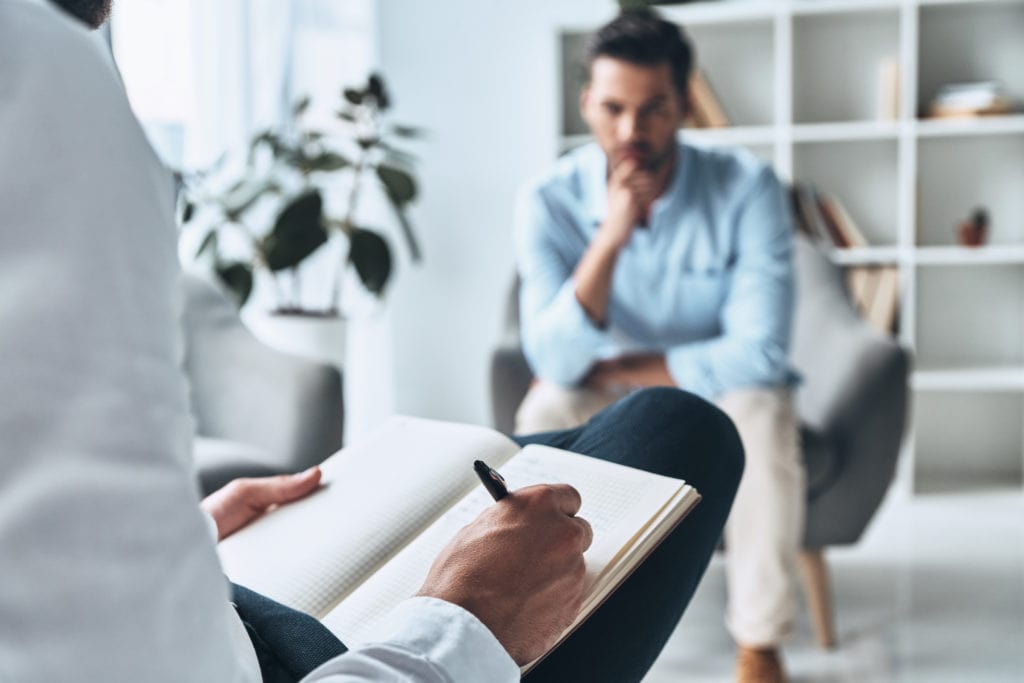 A therapist taking notes during a therapy session with a patient