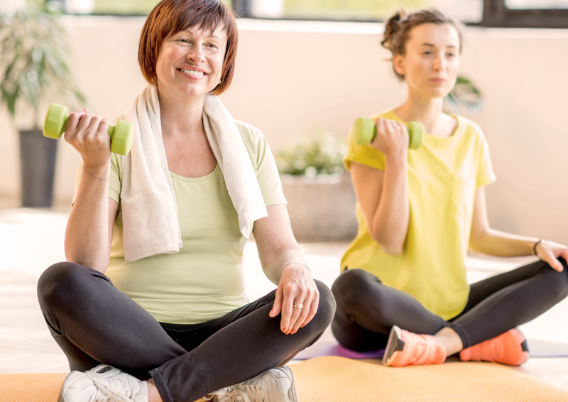 Two women exercising on a mat with weights