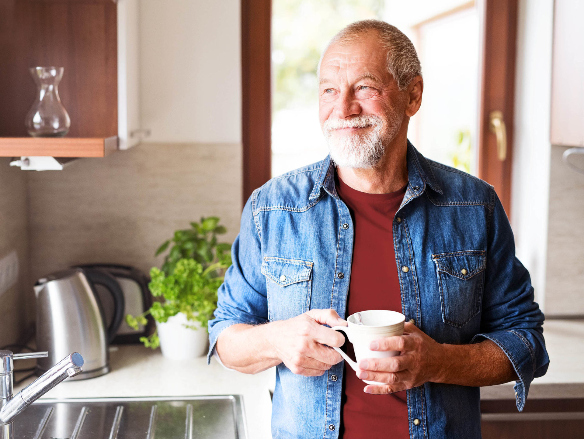 A senior man enjoying coffee in his kitchen