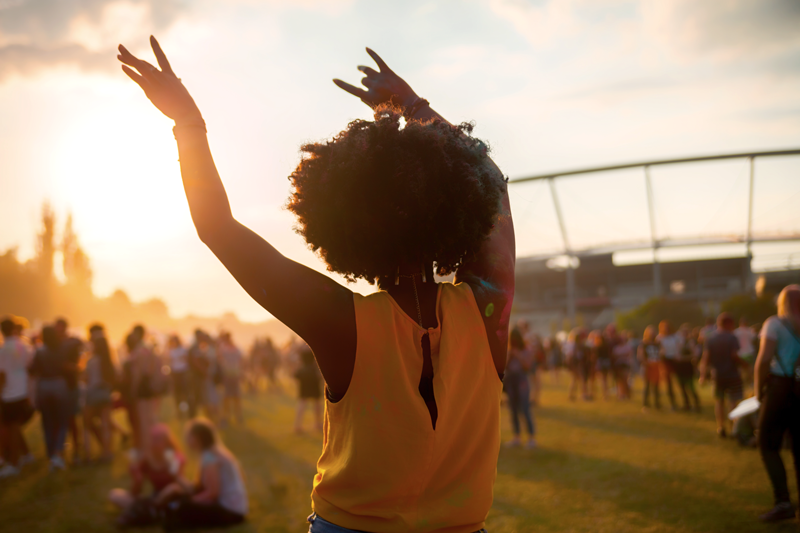 A woman with her hands in the air at an outdoor festival