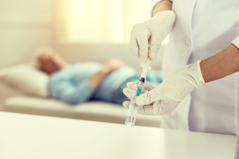 A health care worker preparing a vaccine for a senior patient