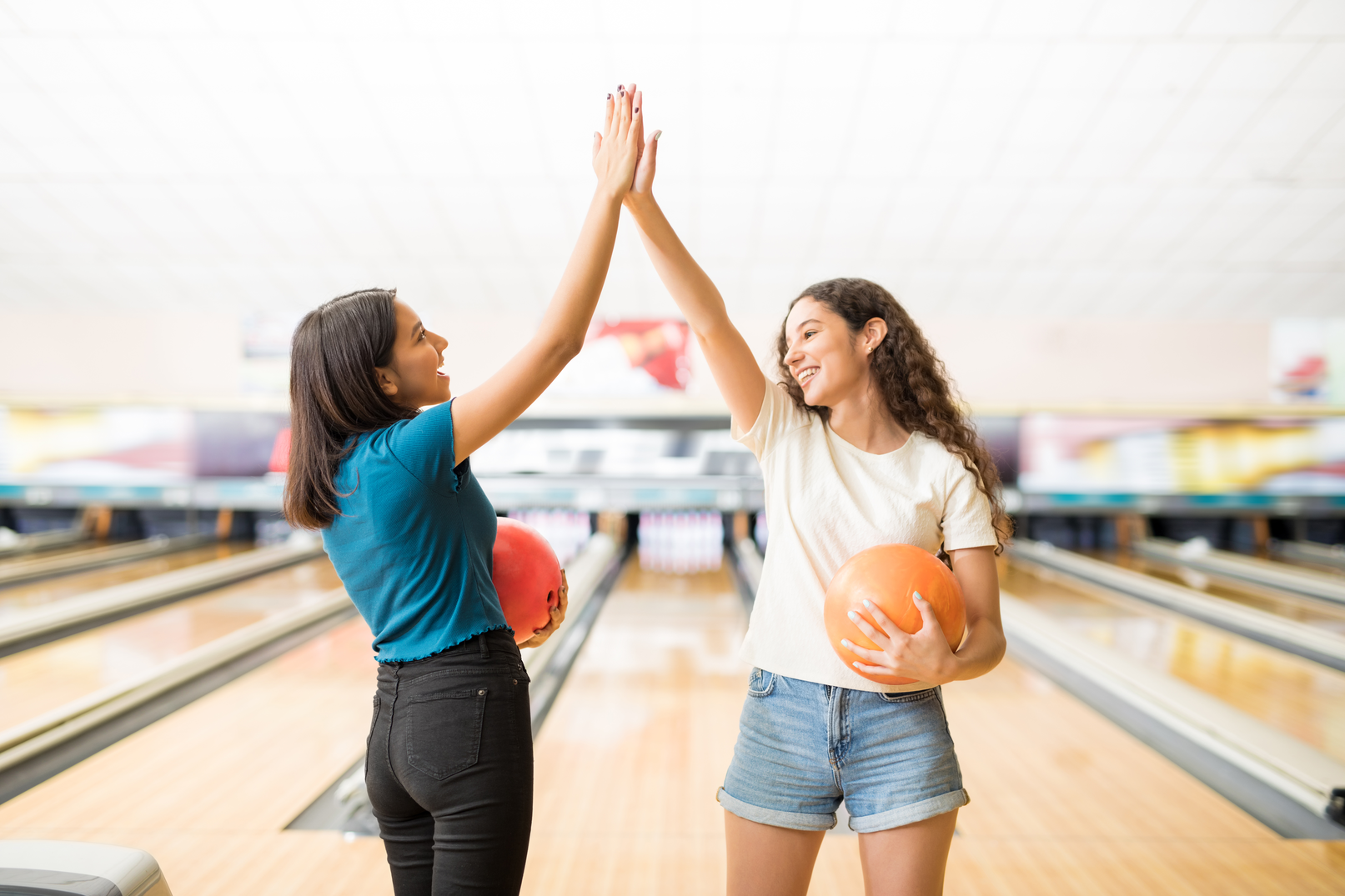 Two young women giving a high-five while bowling