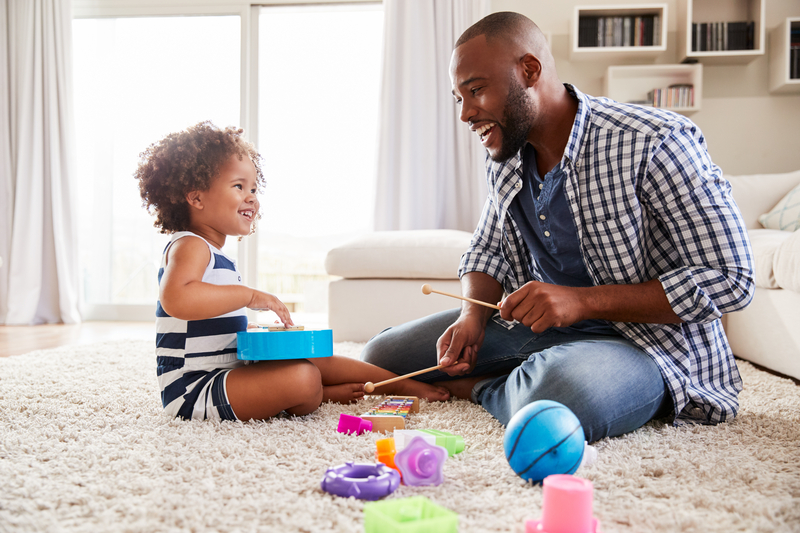 A father and daughter play with musical instrument toys