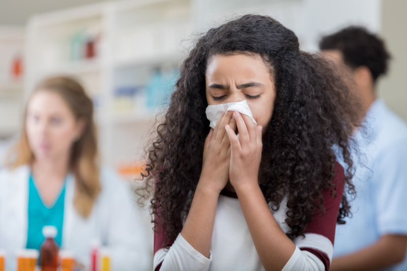 A young girl blows her nose at a pharmacy