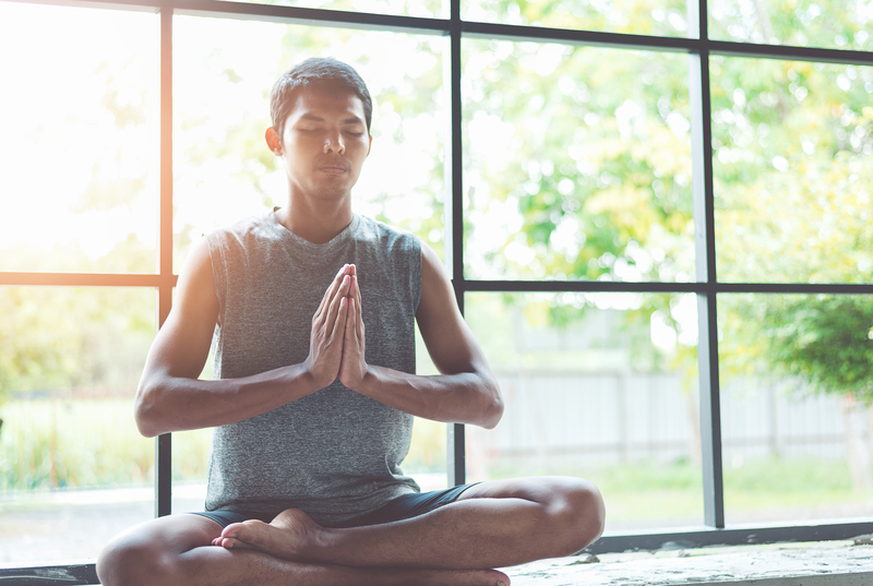 A man meditating in front of window