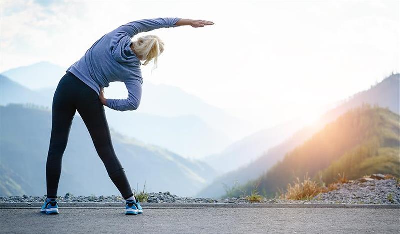 A woman stretching near a misty hills