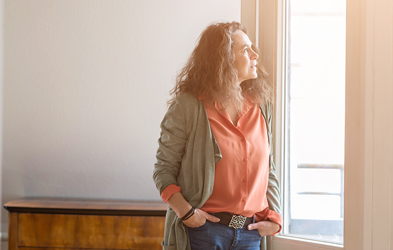 A woman with her hands in her pockets looking out the window