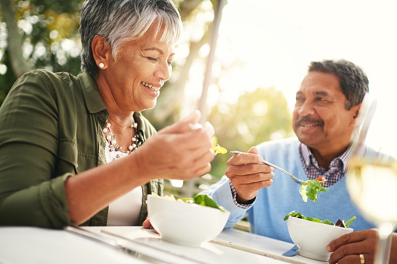 An older couple eating salads at a table together