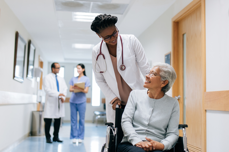 A doctor pushes a patient in a wheelchair in a hospital