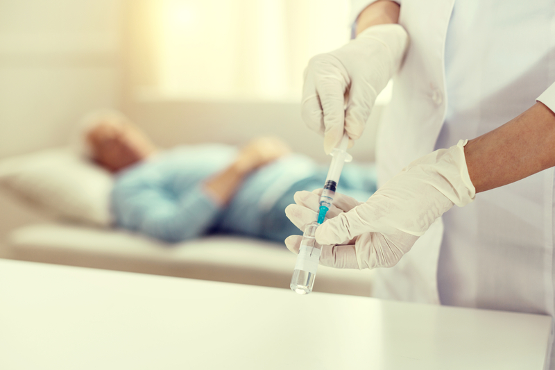 A healthcare professional prepares a vaccine for an elderly patient