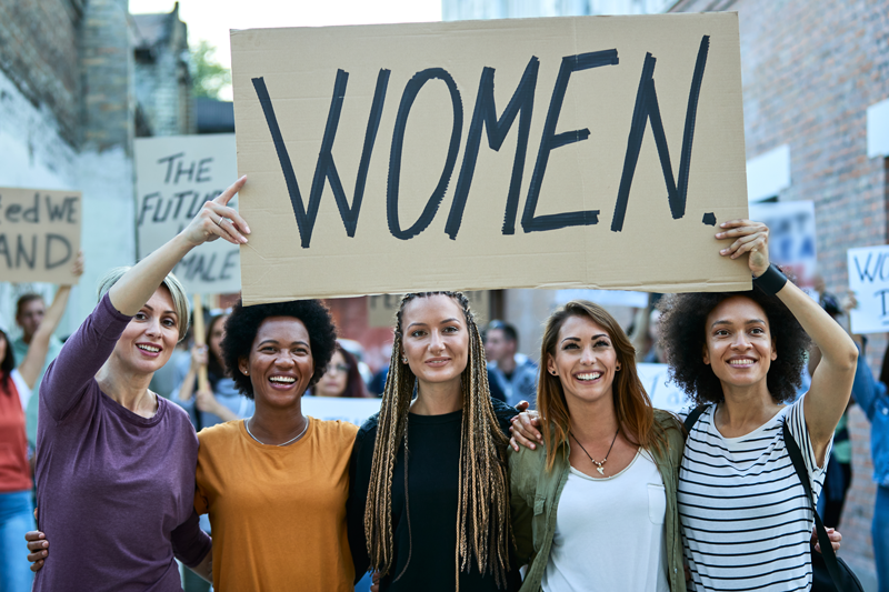 A group of women holding a cardboard sign that says WOMEN for women's rights