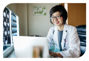 A doctor working at her laptop reviewing x-ray imaging