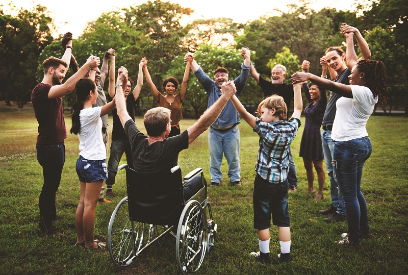 A group of individuals in a field holding hands high in a circle- Diversity, Equity, & Inclusion (DE&I)