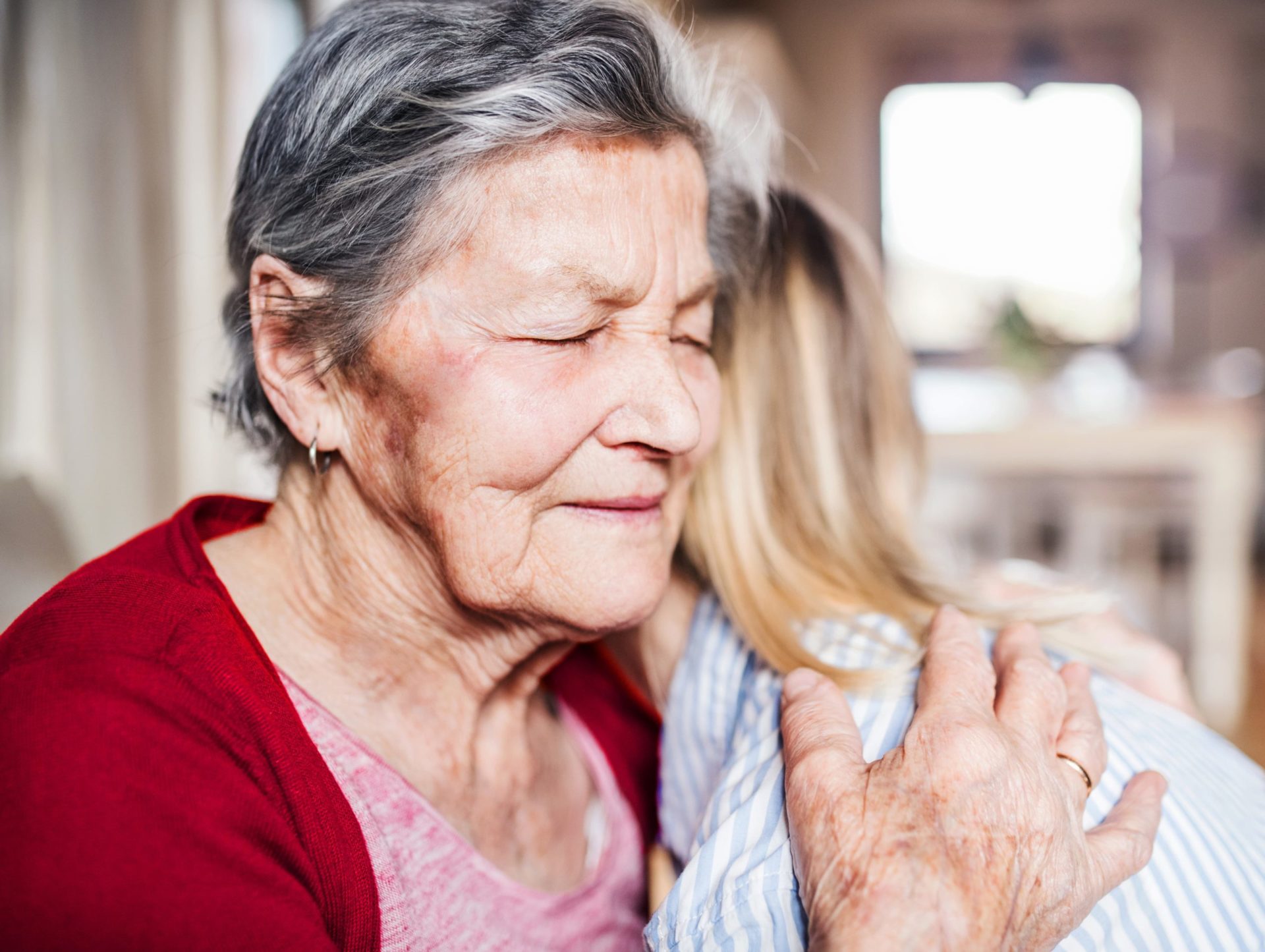 A senior woman hugs a younger woman