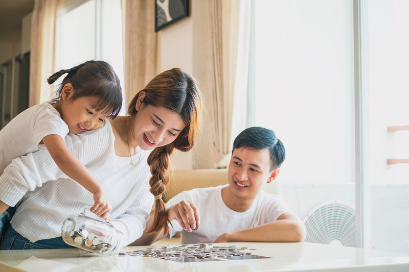 A family of three counting out change from a jar on a table