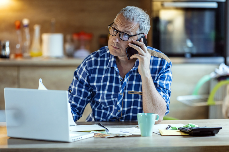 An elder man on his smartphone at his home desk