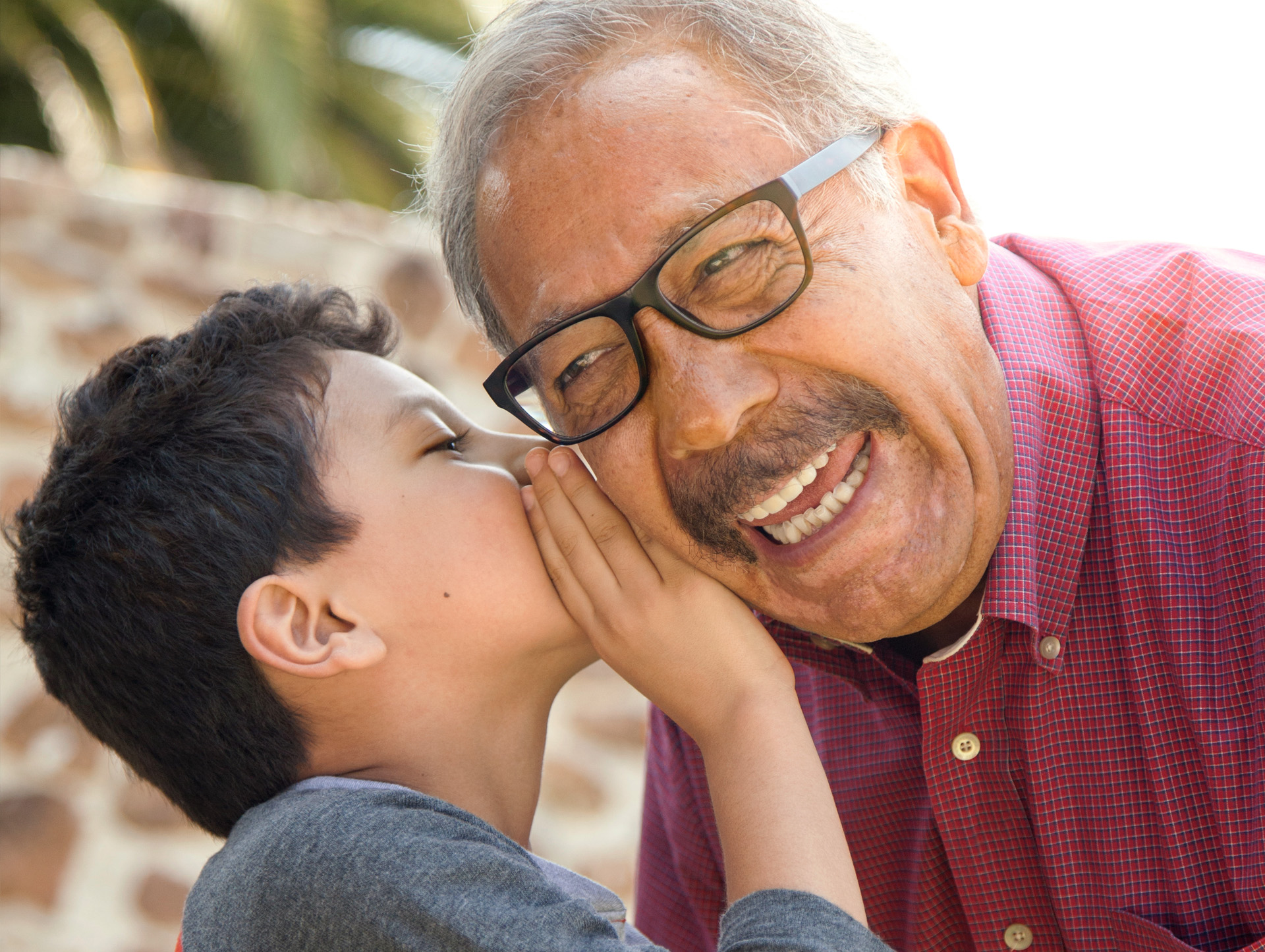 A young boy whispering in the ear of a senior man