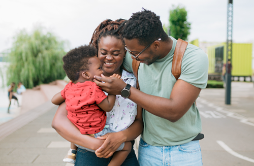 A family of three walking and smiling at each other